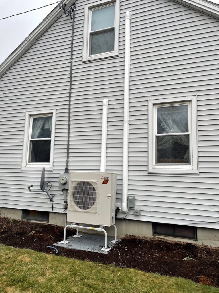 A newly installed outdoor heat pump or mini-split condenser unit on a residential building by All Points HVAC in Worcester, MA.