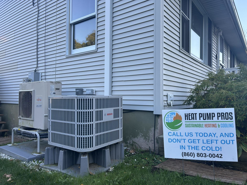 An outdoor Fujitsu and Bosch heat pump system installed by Heat Pump Pros next to a house in Hartford, CT.