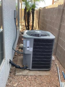 An outdoor HVAC condenser unit installed next to a residential building by Klee's Climate Control in Mesa, AZ.