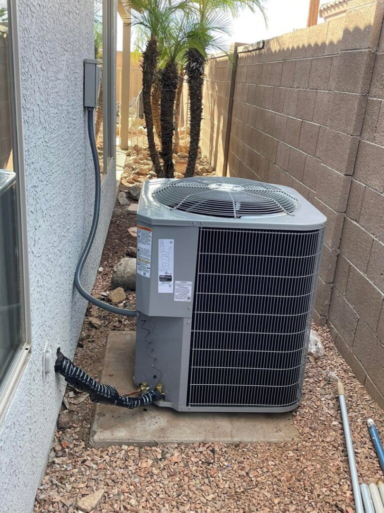 An outdoor HVAC condenser unit installed next to a residential building by Klee's Climate Control in Mesa, AZ.