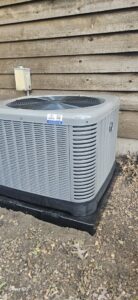An outdoor HVAC condenser unit with a service sticker, installed by Astron Services LLC in Wichita, KS.