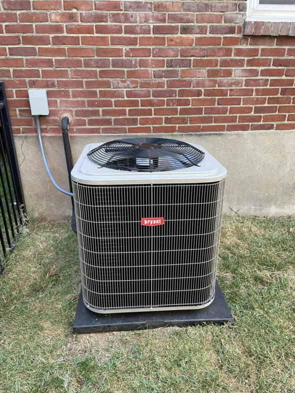 An outdoor Bryant HVAC condenser unit installed next to a brick wall by Bowmans Heating and Air LLC in Middletown, KY