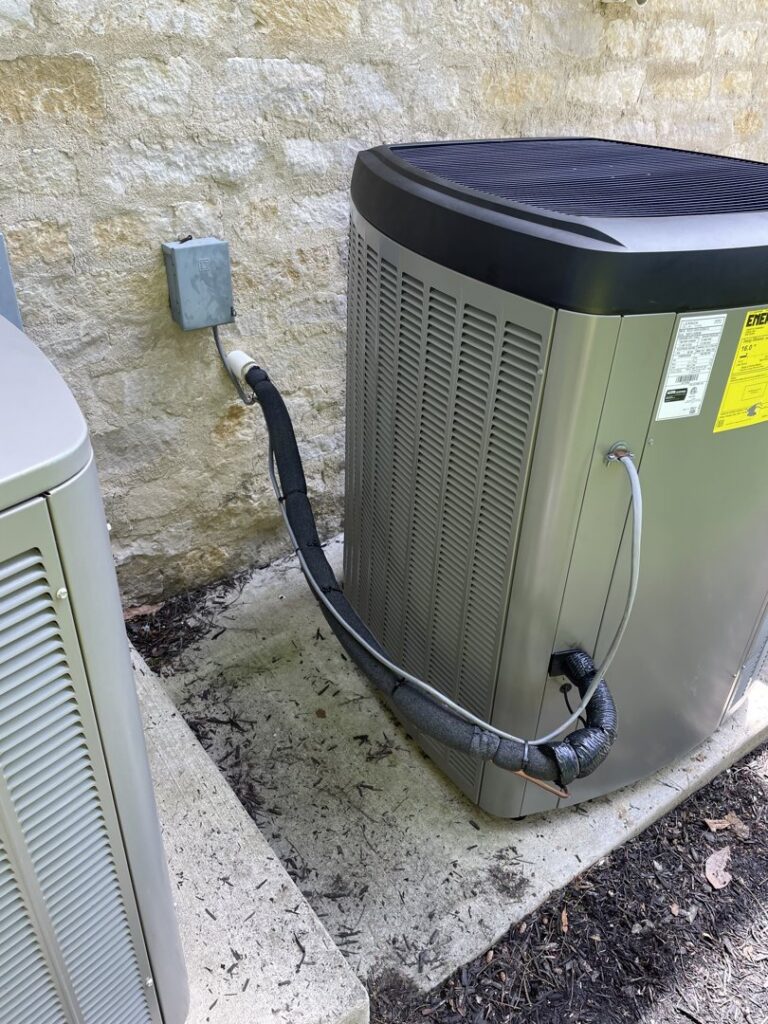 An outdoor HVAC condenser unit installed next to a stone wall by Carpenter Mechanical in Columbus, OH.