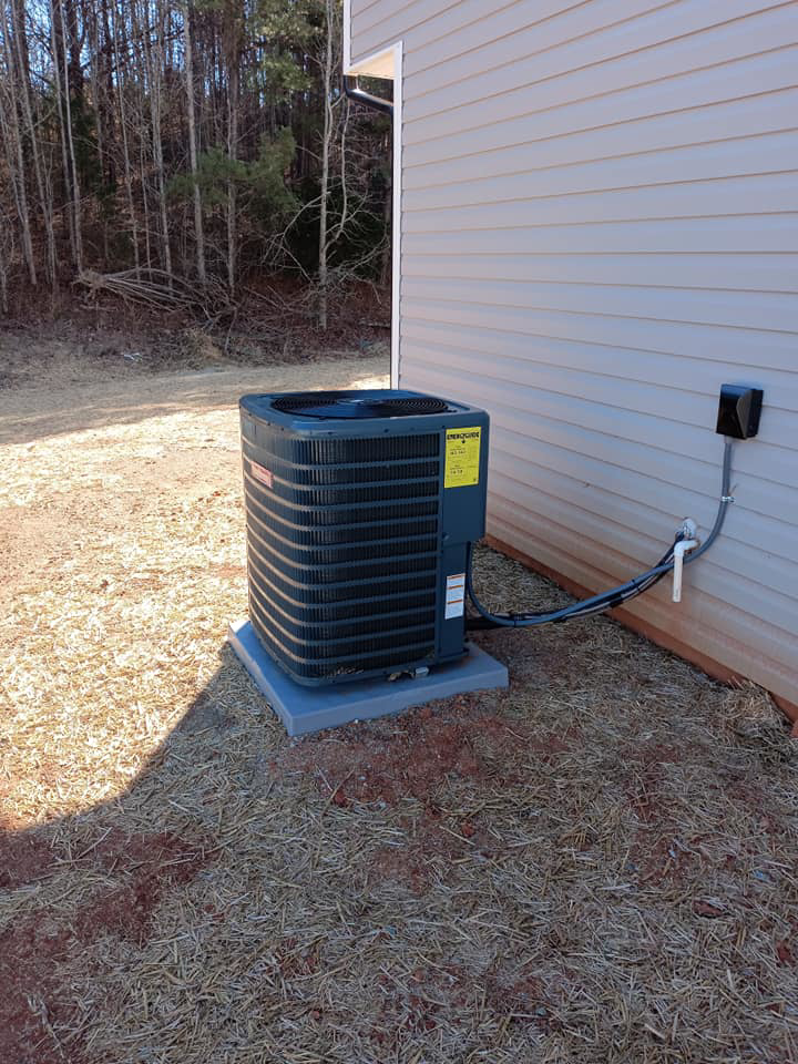 An outdoor HVAC condenser unit installed next to a residential building by Conway's Heating & Air in Concord, NC.