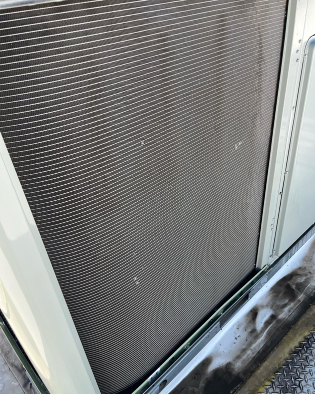 A close-up of an outdoor HVAC condenser unit, showcasing the fins, by CW Mechanical HVACR in Lehi, UT.