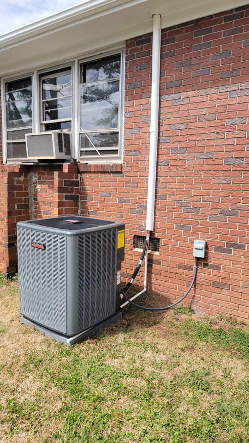 An outdoor HVAC condenser unit installed next to a brick residential home by Efficiency HVAC in Milwaukie, OR.