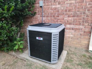 An outdoor HVAC condenser unit installed next to a brick wall by Fusion Heat and Air in Fort Smith, AR.
