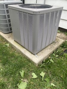 An outdoor HVAC condenser unit on a concrete pad, installed by Improved Comfort in Geneva, IL.