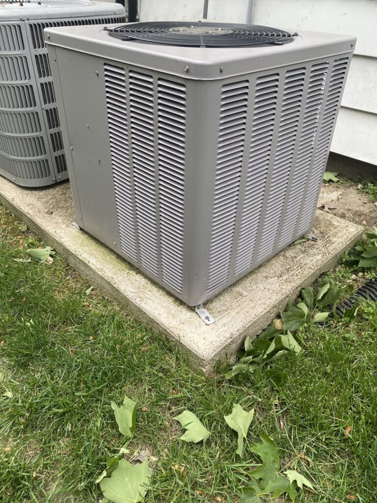An outdoor HVAC condenser unit on a concrete pad, installed by Improved Comfort in Geneva, IL.