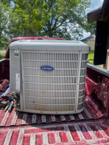 An outdoor HVAC condenser unit being transported in a pickup truck by Reeds heating and air LLC in Mobile, AL.
