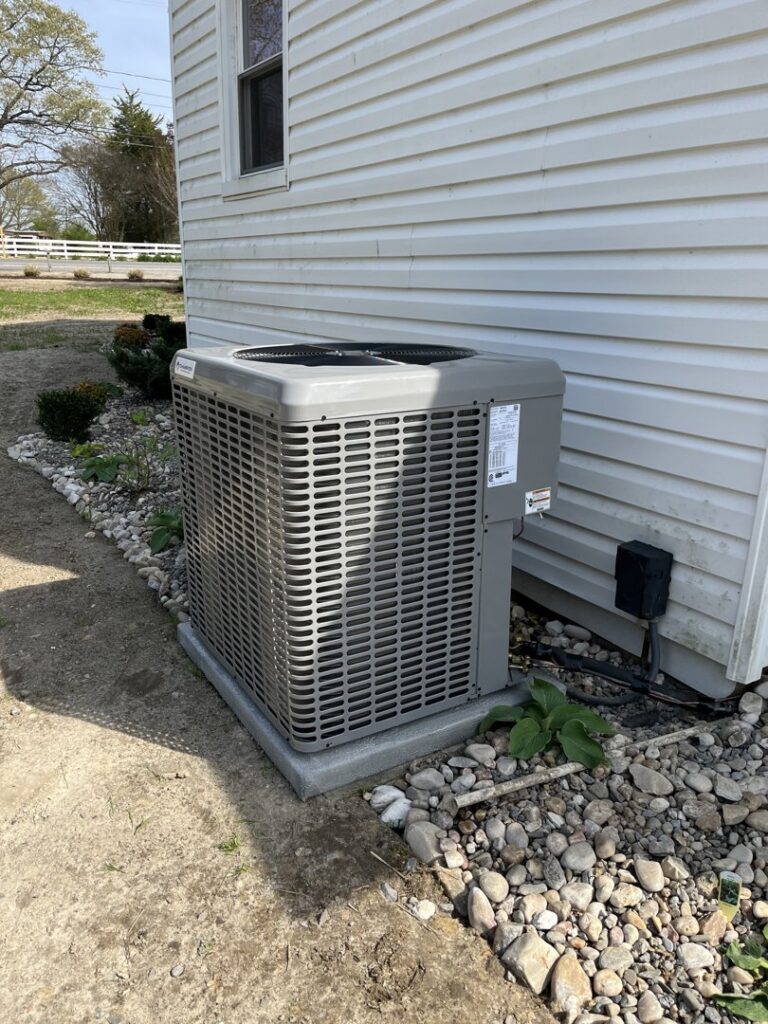 A newly installed outdoor HVAC condenser unit next to a residential building by Coastal Breeze Heating-Cooling-Plumbing in Hampton, VA.