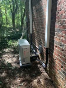 An outdoor HVAC condenser unit installed next to a brick building by Dan Deckard Hvac in Charlotte, NC