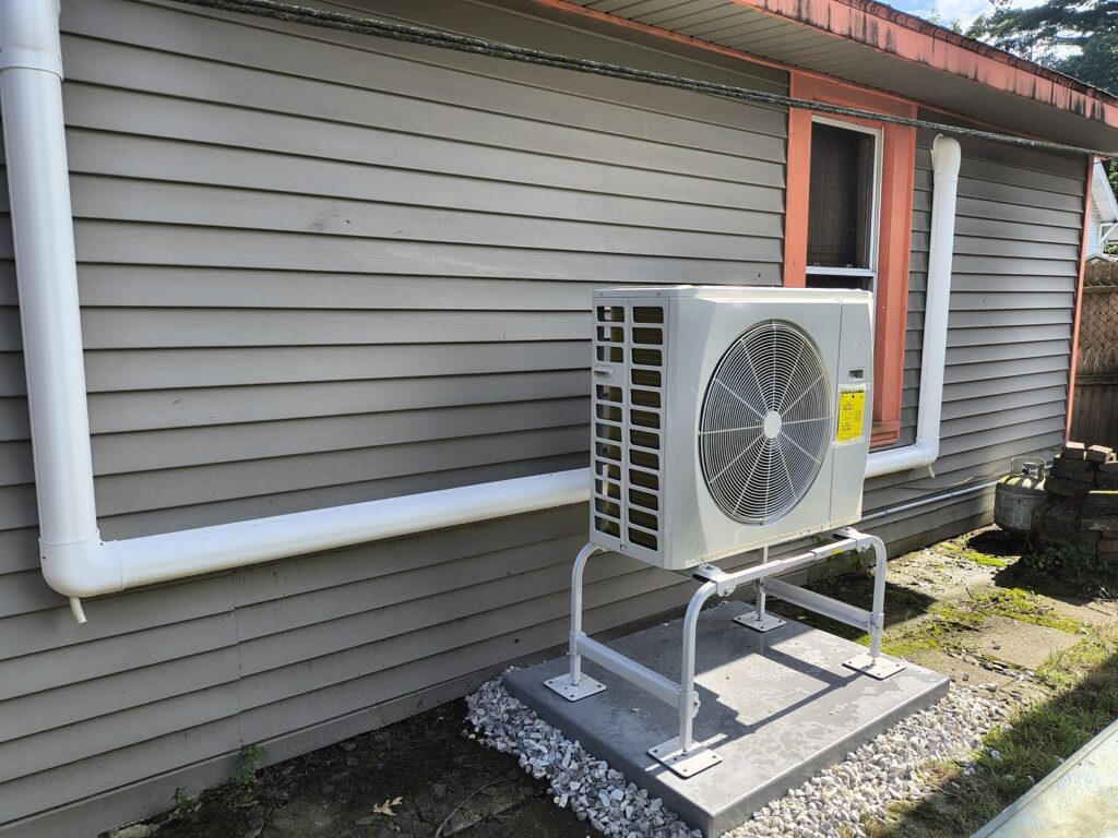 An outdoor HVAC condenser unit installed next to a residential building by HomeWorks Energy in Charlestown, MA.