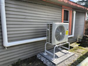 An outdoor HVAC condenser unit installed next to a residential building by HomeWorks Energy in Charlestown, MA.