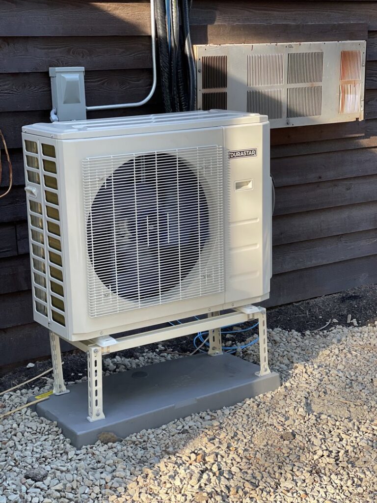 A newly installed Durastar outdoor HVAC condenser unit on a stand next to a building by Jones Heating and Refrigeration in Dickinson, ND.