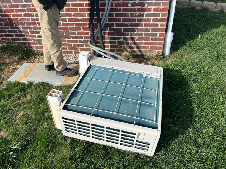 An outdoor HVAC condenser unit being installed or removed next to a brick building by KATS Heating & Cooling in La Grange Park, IL.