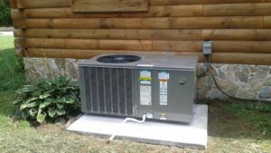 An outdoor HVAC condenser unit installed next to a log cabin by R A Styron Heating & Air Conditioning, Inc. in Chesapeake, VA.