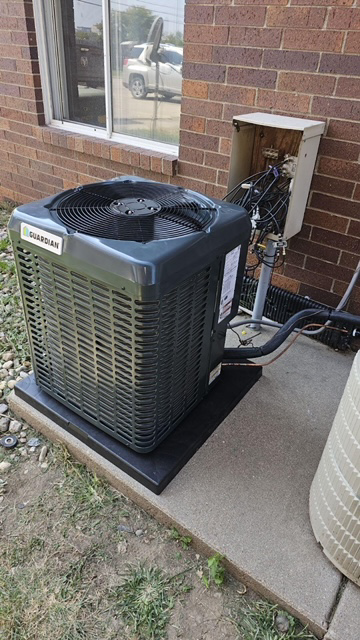 An outdoor HVAC condenser unit installation next to a brick building by Select Heating & Air, Inc in Lincoln, NE.