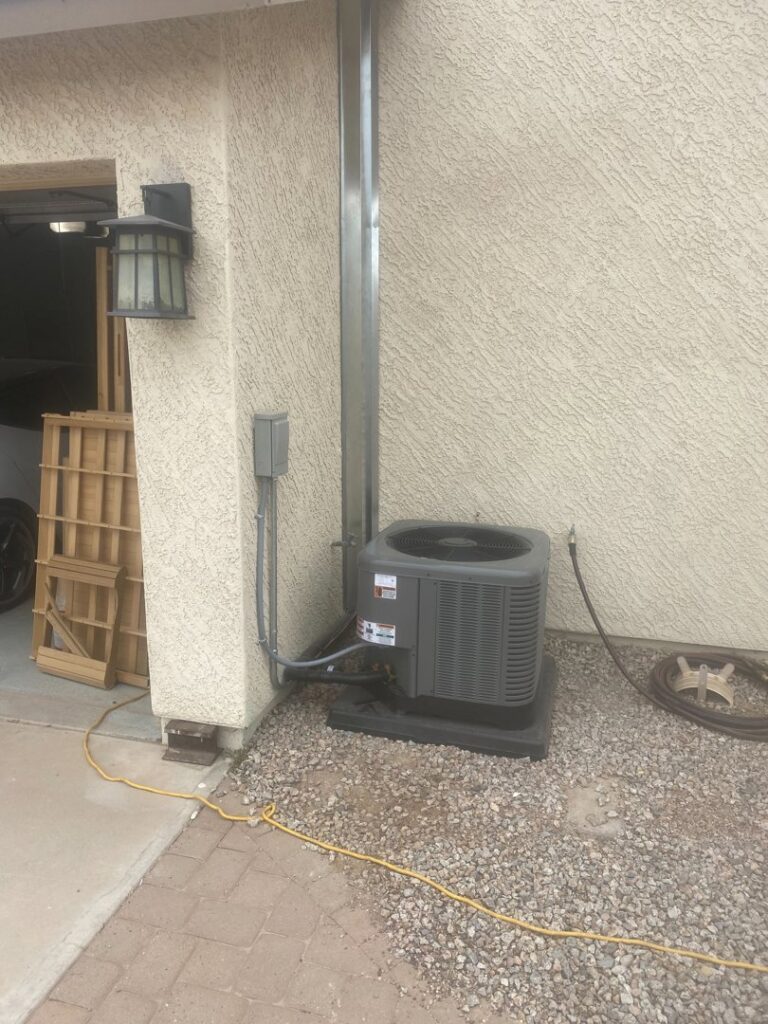An outdoor HVAC condenser unit installed next to a residential building by TK Heating and Air, PLLC in Queen Creek, AZ