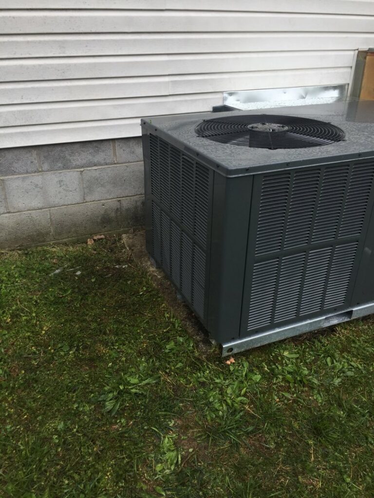 An outdoor HVAC condenser unit installed next to a residential building by Johnson's Heating and Cooling in Clarksville, TN.