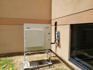 An outdoor Mitsubishi Electric HVAC condenser unit installed next to a building by J.M Heating, Air Conditioning and Refrigeration in Pittsburgh, PA.