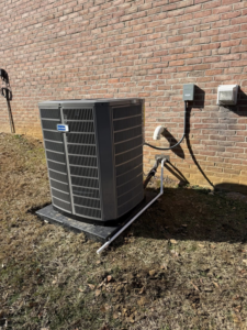 An outdoor HVAC condenser unit installed next to a brick wall by On-Target Heating & Air LLC in Rock Hill, SC.