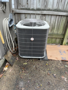 An outdoor Payne HVAC condenser unit installed next to a wooden fence by Pepper Mechanical in Pittsburgh, PA
