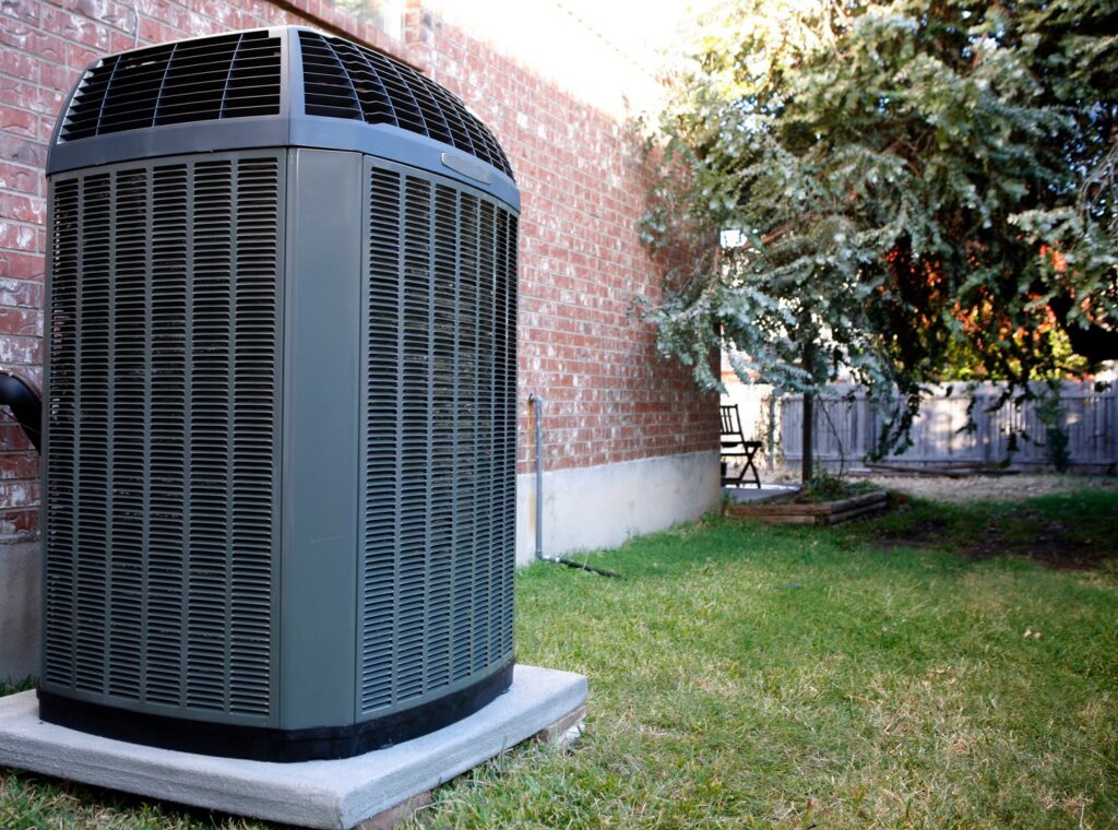 An outdoor HVAC condenser unit installed next to a brick house, serviced by Air Works of Alabama LLC in Mobile, AL.
