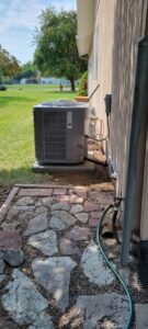 An outdoor HVAC condenser unit is neatly installed next to a residential building by Comfort Systems USA Temp Right Service in Kalispell, MT.