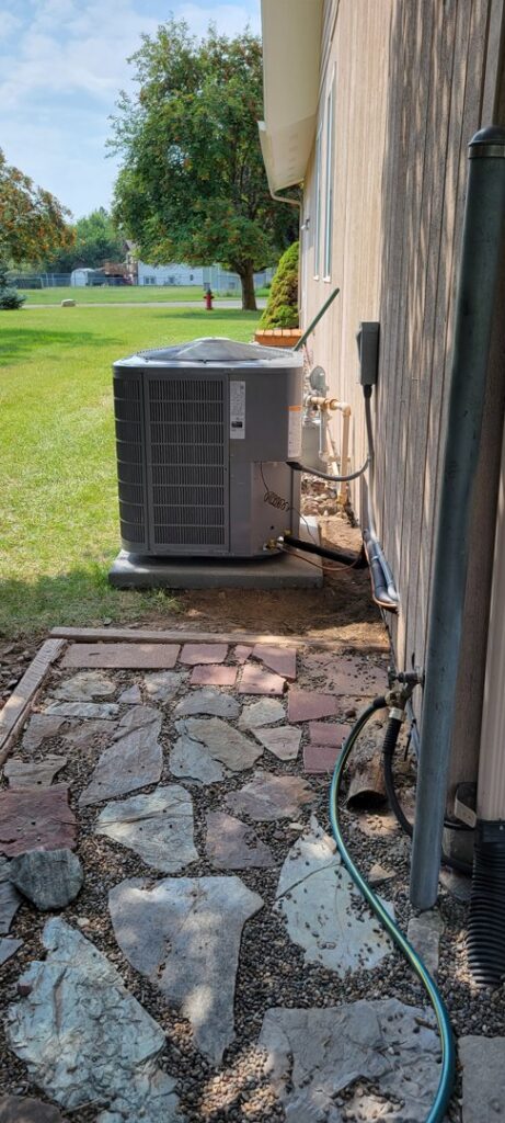 An outdoor HVAC condenser unit is neatly installed next to a residential building by Comfort Systems USA Temp Right Service in Kalispell, MT.