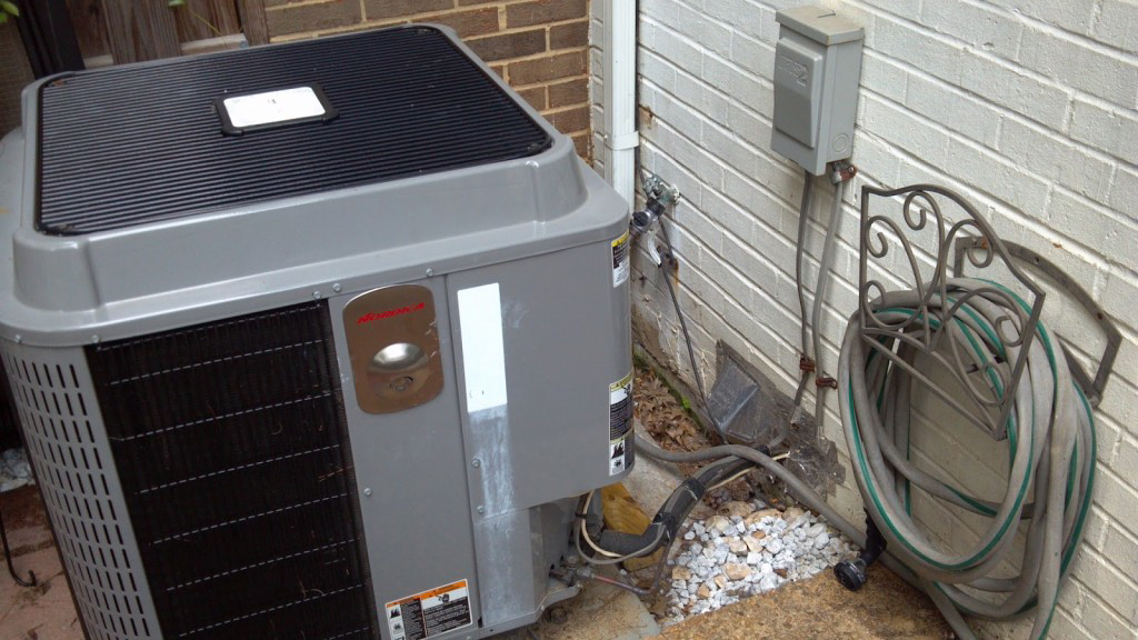 An outdoor HVAC condenser unit installed next to a residential brick wall by Cool Concepts A/C & Heating in San Antonio, TX.
