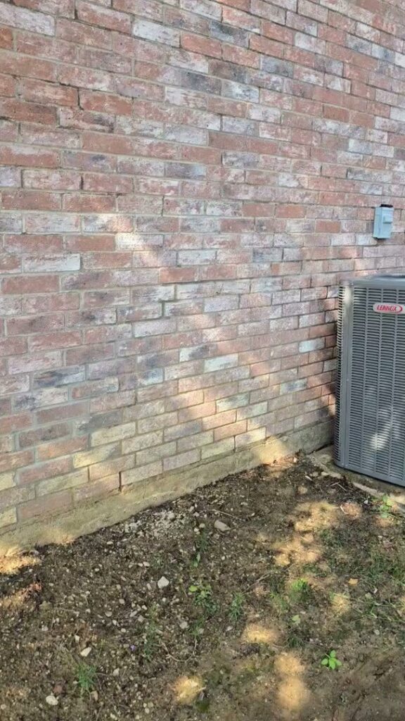 An outdoor HVAC condenser unit installed next to a brick residential wall by Harlen Johnson Heating & Air in Dallas, TX.