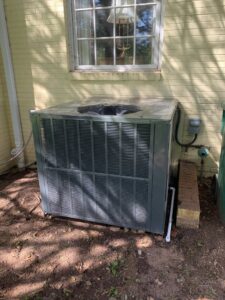 An outdoor HVAC condenser unit installed at a residential property by Kelley's Heating & Air in Dadeville, AL
