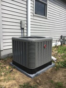 An outdoor HVAC condenser unit installed next to a residential home with siding by Cool Tech Heating & Cooling in East Peoria, IL.