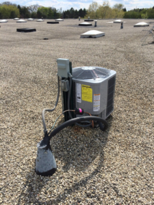 An outdoor HVAC condenser unit installed on a gravel rooftop by Corbe Heating and Air Conditioning in Elgin, IL.