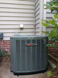 An outdoor Trane HVAC condenser unit installed next to a residential building by Ryans Ambient Air in Portsmouth, VA.