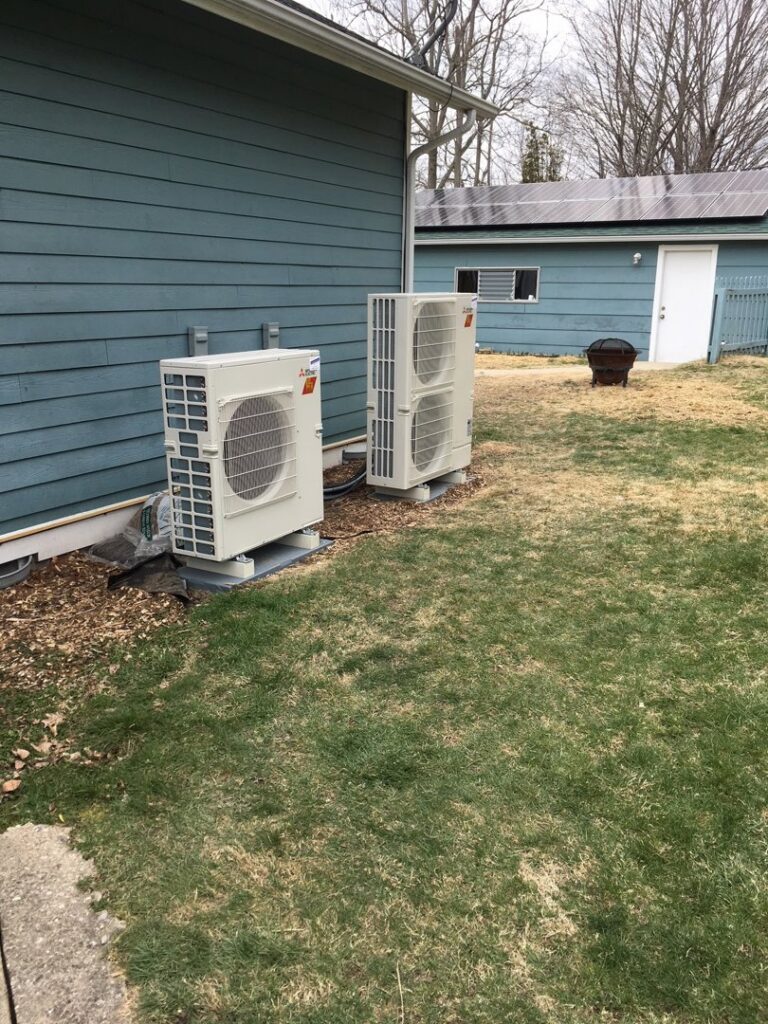 Two outdoor HVAC condenser units installed next to a residential building by Commercial Service in Bloomington, IN.