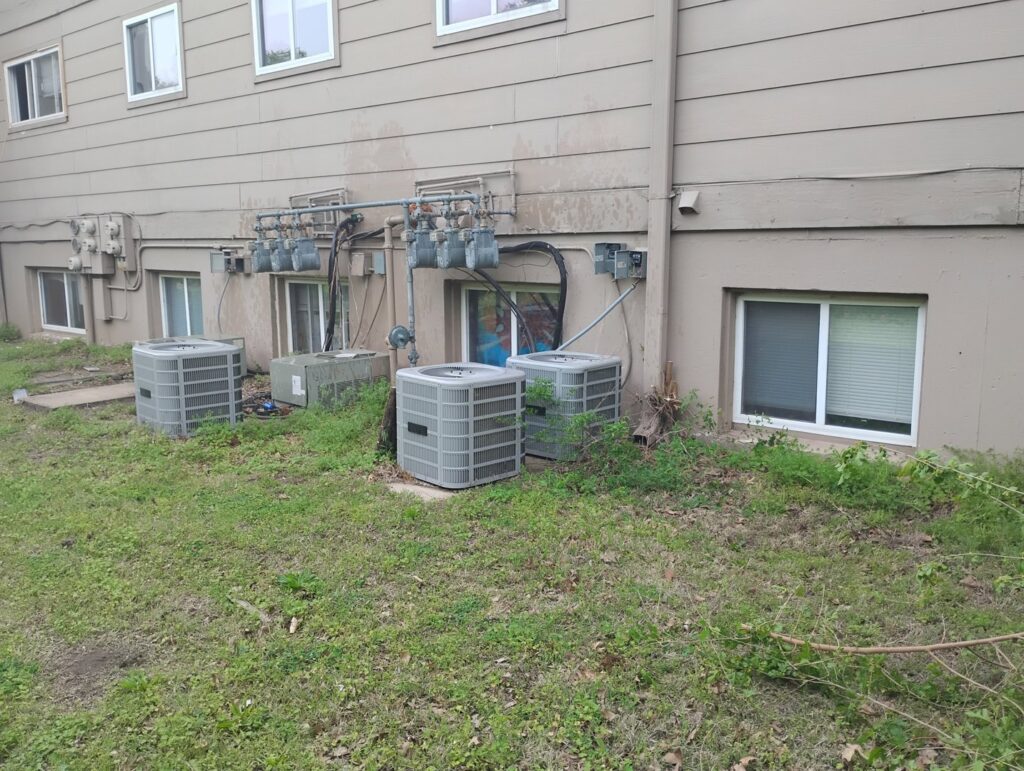 Several outdoor HVAC condenser units installed along a building by Cool Guys Heating & Air in Georgetown, TX.