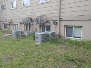Several outdoor HVAC condenser units installed along a building by Cool Guys Heating & Air in Georgetown, TX.