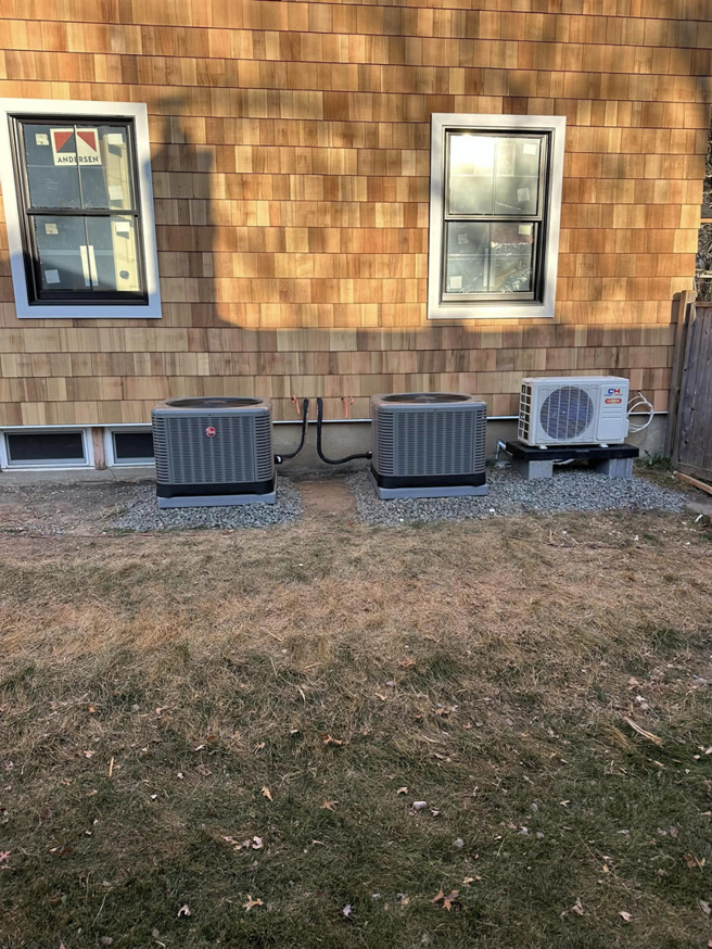 Three outdoor HVAC condenser units installed next to a residential building by R&R Climate Systems in Newark, NJ