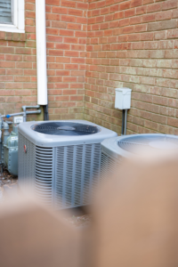 Two outdoor HVAC condenser units installed next to a brick house by Travis Crawford Heating, Cooling, Plumbing & Electrical in Charlotte, NC.
