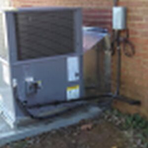 An outdoor HVAC system installation with ductwork next to a brick wall by Dan Deckard Hvac in Charlotte, NC