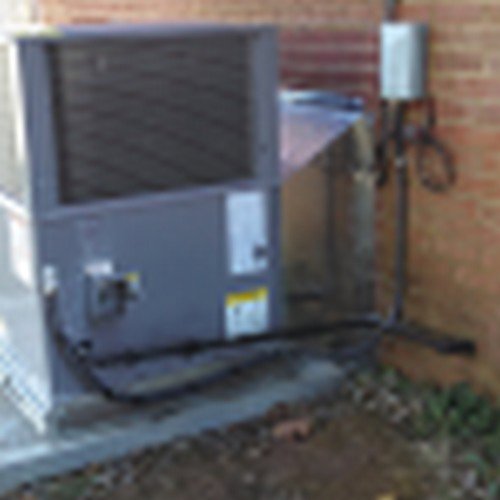 An outdoor HVAC system installation with ductwork next to a brick wall by Dan Deckard Hvac in Charlotte, NC