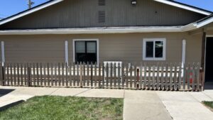An outdoor HVAC condenser unit situated behind a small wooden fence, installed by Service Kings Heating and Air in Jamestown, ND.