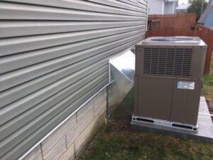 An outdoor HVAC unit with new ductwork connecting to a home, installed by Dodrill Comfort & Energy Solutions in Cross Lanes, WV