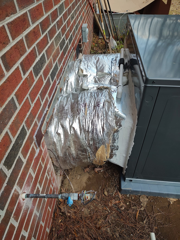 An outdoor HVAC unit with insulated ductwork installed next to a brick house by NAS Heating & Air in Fayetteville, NC.