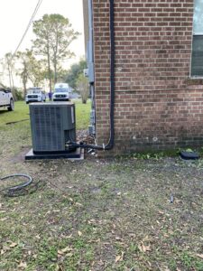 An outdoor HVAC unit installation next to a brick building by Alpha HVAC LLC in Alexandria, LA.