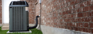 An outdoor HVAC unit installed next to a brick residential building by Climate Specialists in Omaha, NE.