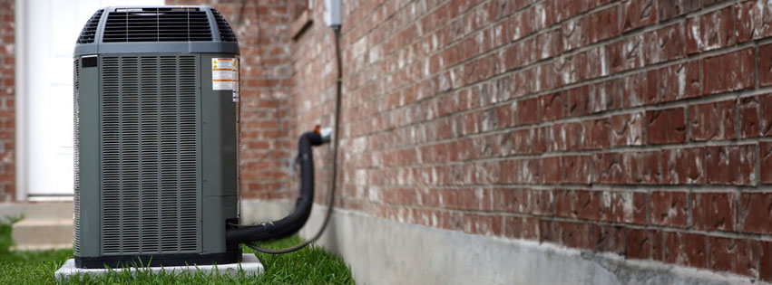 An outdoor HVAC unit installed next to a brick residential building by Climate Specialists in Omaha, NE.