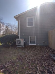 An outdoor HVAC unit, likely a heat pump or AC condenser, installed by CMAGS HVAC INC next to a home in Warwick, RI.